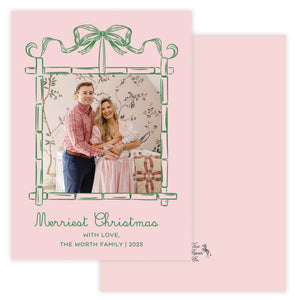 Christmas card with green bamboo and bow frame for photo and pink background.