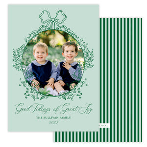 Holiday card with two children and decorative text and a bow floral frame on a light green background
